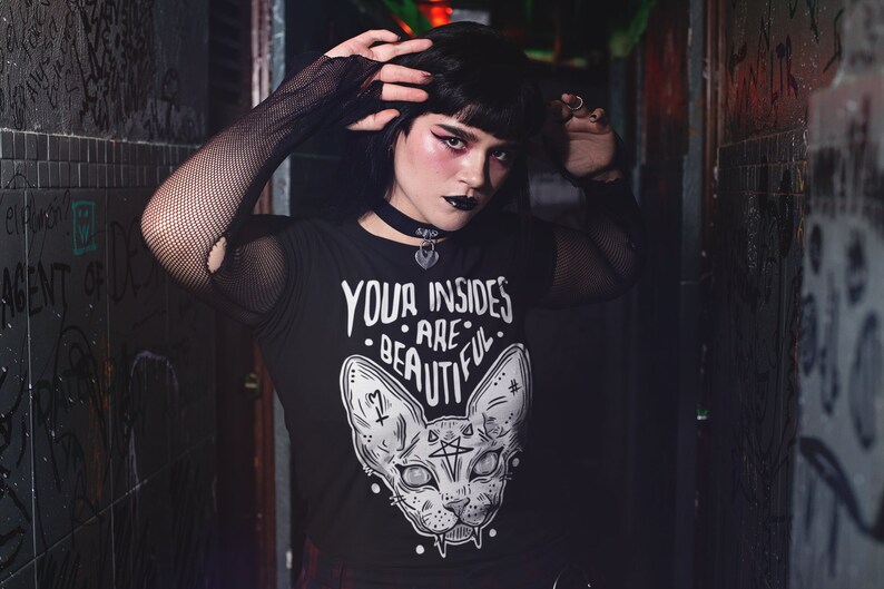 May include: A black t-shirt with a white graphic of a cat with the text "Your insides are beautiful." The cat has large eyes and a pentagram on its forehead.