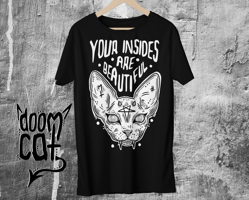 May include: Black t-shirt with a white graphic of a sphinx cat with a pentagram on its forehead and the text "YOUR INSIDES ARE BEAUTIFUL".