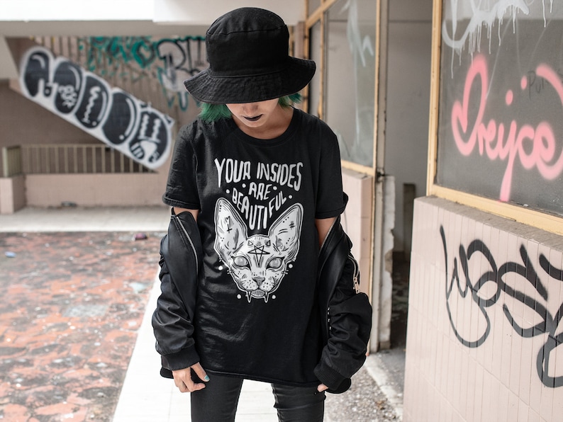 May include: A black t-shirt with a graphic of a cat's head and the text "Your insides are beautiful".