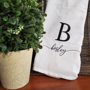 May include: White kitchen towel with a black letter B and the name "Bosley" written in cursive.