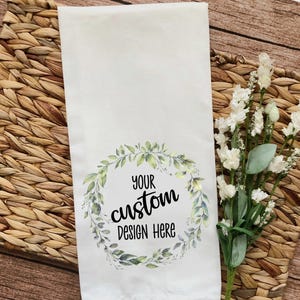 May include: White kitchen towel with a green watercolor wreath and the text "Your custom design here".