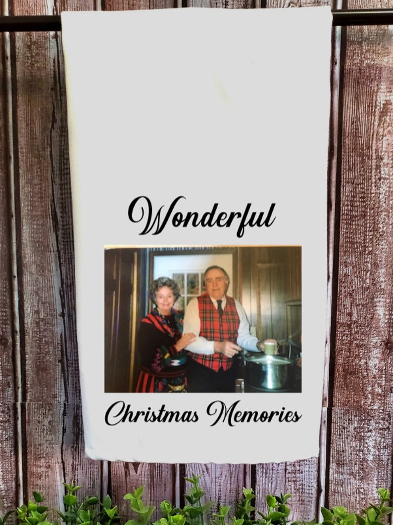 May include: A white kitchen towel with a black and white photo of an older couple in a kitchen. The text "Wonderful Christmas Memories" is printed below the photo.