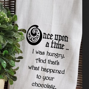 May include: White kitchen towel with black text that reads "Once upon a time... I was hungry. And that's what happened to your chocolate."
