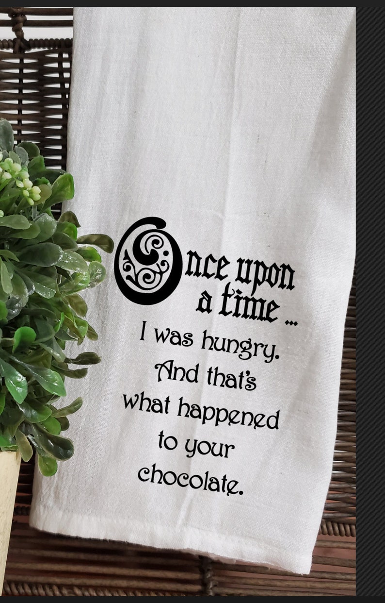 May include: White kitchen towel with black text that reads "Once upon a time... I was hungry. And that's what happened to your chocolate."