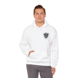 May include: White hooded sweatshirt with a front pocket and a gray shield emblem on the chest. The emblem features a stylized design. The sweatshirt is made of a soft material and is suitable for casual wear.