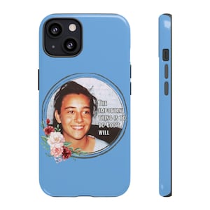 May include: A light blue phone case featuring a portrait of a smiling person within a circular frame. The frame includes the text "THE IMPORTANT THING IS TO DO GOD'S WILL" and is decorated with floral accents in shades of red and pink.