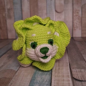 May include: A crocheted stuffed animal in the shape of a lion with green and white fur. The lion has a white face with green eyes and a green nose.
