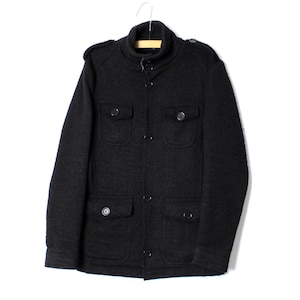 Könnte beinhalten: Dunkelgraue Jacke mit Stehkragen, Knopfverschluss und vier Vordertaschen. Die Jacke hängt an einem Holzbügel vor weißem Hintergrund. Die Jacke hat Schulterklappen.
