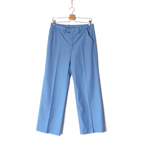 K&ouml;nnte beinhalten: Eine hellblaue, weite Hose, die an einem Holzb&uuml;gel h&auml;ngt.