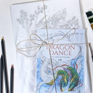 May include: A set of three adult coloring pages featuring a dragon dance. The cover shows two dragons, one green and one white, intertwined in a dance. The title "Dragon Dance" is printed in white on a blue background. The text "Set of 3 adult colouring pages" is printed below the title.