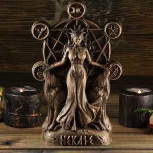 May include: A wooden statue of Hekate, the Greek goddess of witchcraft, magic, and crossroads. She is depicted standing with two wolves on either side of her, and a pentagram behind her. The statue is painted in a dark brown colour and has a rustic finish.