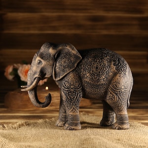 Feng Shui home decor featuring a handcrafted wooden elephant statue on a rustic table next to a brass lantern.
