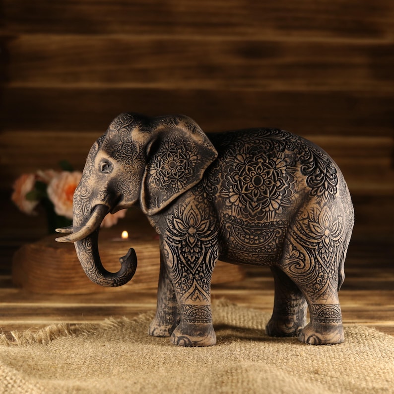 Feng Shui home decor featuring a handcrafted wooden elephant statue on a rustic table next to a brass lantern.
