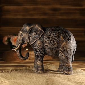 Tribal style wood carving of a majestic elephant, handmade spiritual talisman with realistic skin and ornament definition.
