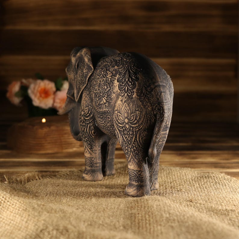 Close-up of a carved wooden mandala pattern and lotus filigree on a handmade elephant figurine.