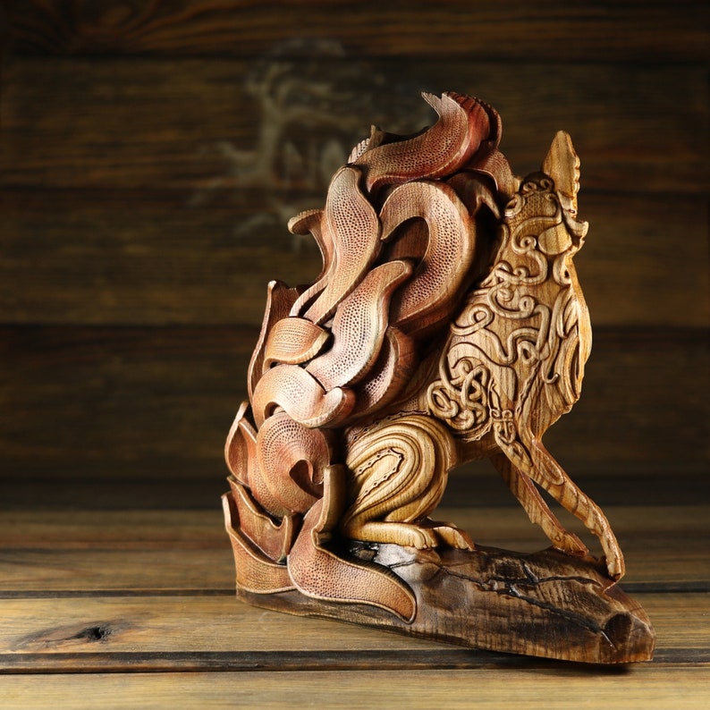 May include: A wooden sculpture of a wolf with intricate carvings. The wolf is depicted in a sitting position with its head turned to the side. The sculpture is made of a light brown wood and has a natural finish.