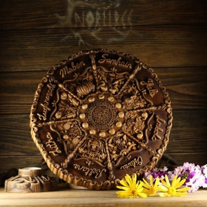 Peut inclure: Une roue en bois avec des sculptures repr&eacute;sentant les huit sabbats de la Roue de l'Ann&eacute;e. La roue est brune et a une teinte brun fonc&eacute;. Les sabbats sont &eacute;tiquet&eacute;s dans le sens des aiguilles d'une montre&nbsp;: Samhain, Yule, Imbolc, Ostara, Beltane, Litha, Lammas et Mabon.