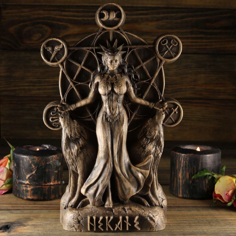May include: A wooden statue of the Greek goddess Hekate, depicted with a crown, flowing robes, and two wolves. The statue is set against a wooden background and features a geometric design with symbols.