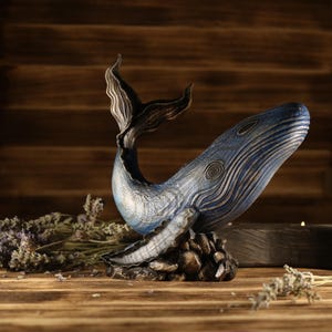 A full side view of the hand-carved wood blue whale figurine, showcasing the detailed ocean decor sculpture facing right. The sea animal sculpture features intricate textures, deep blue tones, and an upward-curved tail.