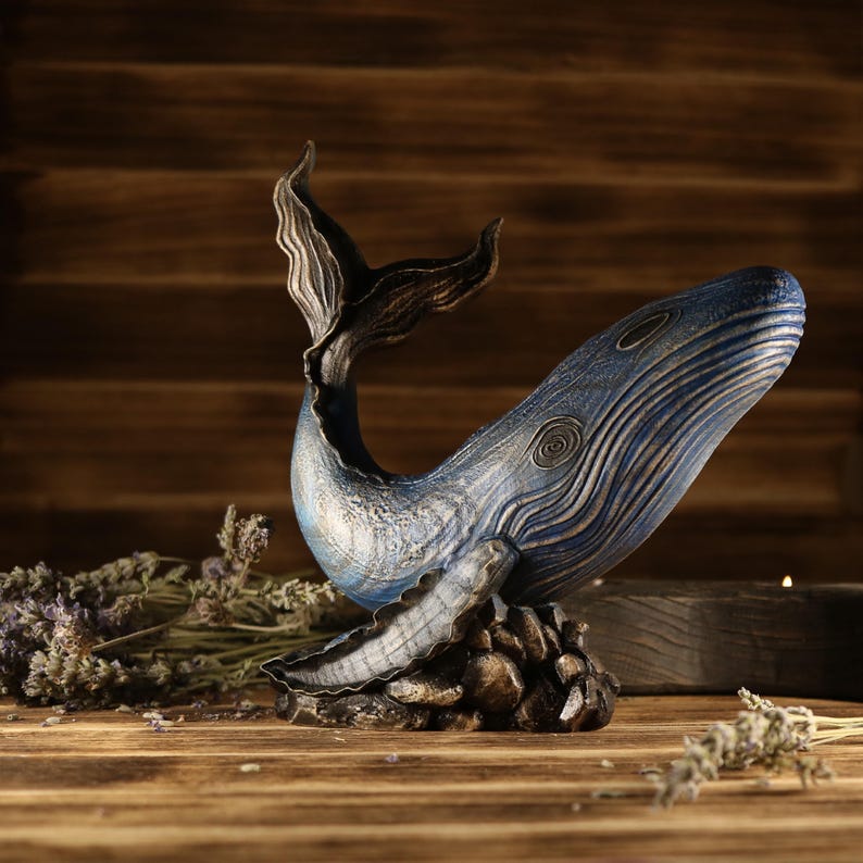 A full side view of the hand-carved wood blue whale figurine, showcasing the detailed ocean decor sculpture facing right. The sea animal sculpture features intricate textures, deep blue tones, and an upward-curved tail.