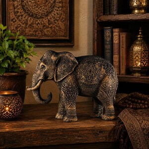 Bohemian style wood carving of a standing black elephant with detailed mandalas and an antique metallic patina finish.