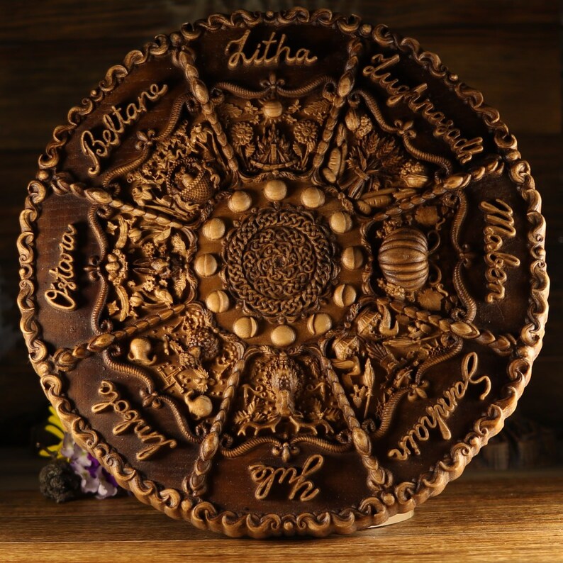 Peut inclure: Une roue en bois avec des sculptures repr&eacute;sentant les huit sabbats de la Roue de l'Ann&eacute;e. La roue est brune et a une bordure brun fonc&eacute;. Les sabbats sont &eacute;tiquet&eacute;s dans le sens des aiguilles d'une montre&nbsp;: Beltane, Litha, Lughnasadh, Mabon, Samhain, Yule, Imbolc et Ostara.