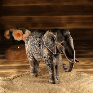 Sacred wealth protection idol, wood-carved elephant with a low trunk stance and realistic tusks.