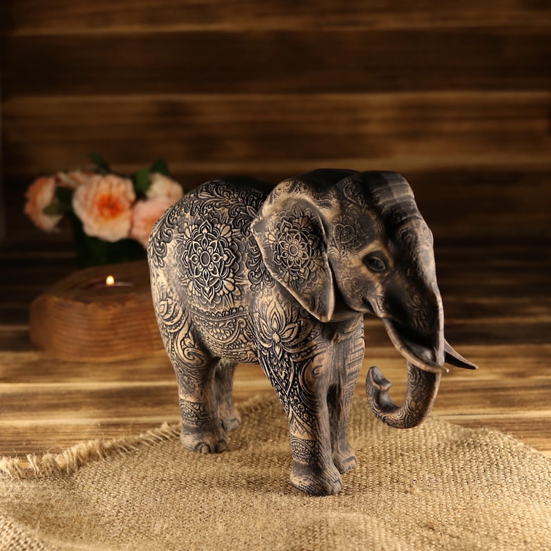 Sacred wealth protection idol, wood-carved elephant with a low trunk stance and realistic tusks.