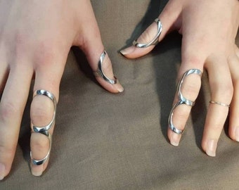 Op de afbeelding: Drie zilveren vinger ringen met open ontwerpen. De ringen worden gedragen op de wijsvinger, middelvinger en ringvinger van een hand.