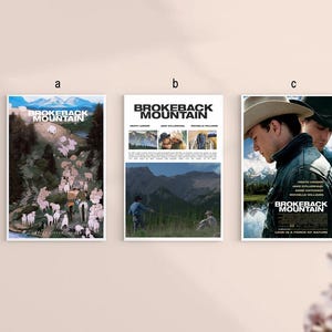 May include: Three framed movie posters for "Brokeback Mountain" are displayed. The posters feature images of the film's stars and scenes from the movie. The posters are mounted on a light-colored wall.
