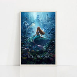 Puede incluir: Un p&oacute;ster enmarcado que presenta una sirena con largo cabello rojo y una cola turquesa, sentada en una roca bajo el agua. El p&oacute;ster tiene una combinaci&oacute;n de colores azul y verde, con las palabras "THE LITTLE MERMAID" en la parte inferior.