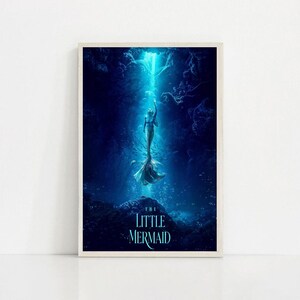 Puede incluir: Un p&oacute;ster enmarcado que representa a una sirena ascendiendo hacia un haz de luz en una escena submarina azul profundo. El t&iacute;tulo "THE LITTLE MERMAID" se muestra en la parte inferior en texto blanco. La obra de arte evoca asombro y fantas&iacute;a.