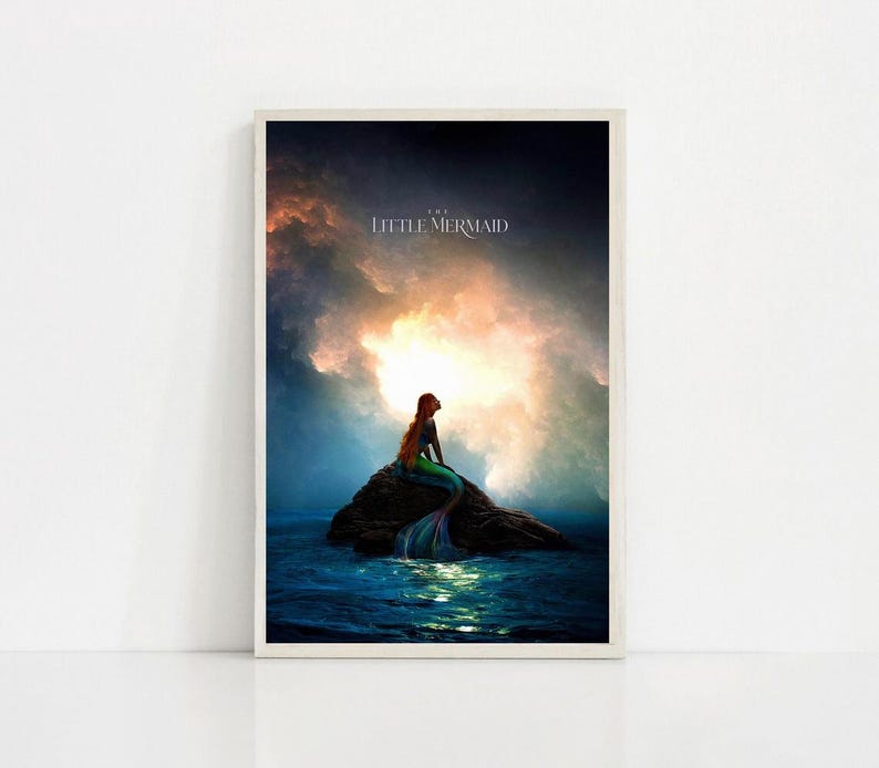 Puede incluir: Impresi&oacute;n enmarcada de una sirena sentada en una roca en el oc&eacute;ano. La sirena tiene pelo largo rojo y una cola verde y azul. El fondo muestra un cielo dram&aacute;tico con el texto "THE LITTLE MERMAID".