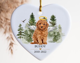 May include: White heart-shaped ceramic ornament featuring a watercolour illustration of a brown poodle with angel wings and a halo. The ornament is inscribed with the text "BUDDY 2010-2022".