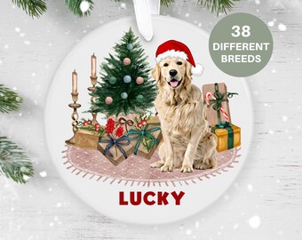 May include: A white ceramic Christmas ornament featuring a golden retriever dog wearing a Santa hat, sitting in front of a Christmas tree with presents and candles. The ornament has the word "LUCKY" written on it.