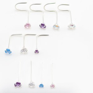 May include: A set of ten nose rings with different colored gemstones. The rings are made of silver and have a simple, elegant design. The gemstones are pink, purple, blue, and clear.