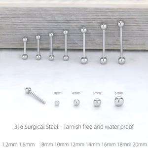 Può includere: Una collezione di piercing per la lingua a barbell di colore argento in varie misure. L'immagine mostra più barbell con estremità a sfera, che vanno da piccole a grandi. Il testo sull'immagine indica misure da 1,2 mm a 20 mm. Il testo indica anche che il materiale è acciaio chirurgico 316.