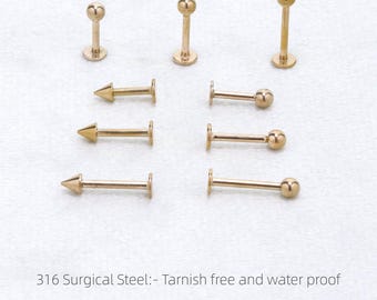 May include: A selection of gold-coloured body jewellery, including labret studs with ball and cone ends. The image includes text indicating the jewellery is made of 316 surgical steel and is tarnish-free and waterproof. Sizes are listed in millimetres.