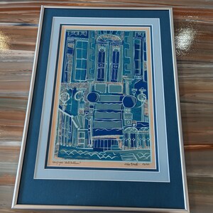 May include: A framed blue and white print of a building with a door and windows. The print is titled "Cityscape Hotel Room" and signed "John Black - 53/100".