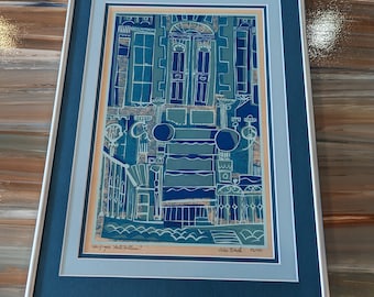 May include: A framed blue and white print of a building with a door and windows. The print is titled "Cityscape Hotel Room" and signed "John Black - 53/100".
