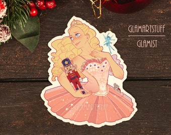 May include: A pink and white ballerina doll with blonde hair, holding a toy nutcracker and a mouse. The doll is wearing a pink tutu and a crown. The background is a wooden surface with the text "Glamartstuff" and "Glaміст" in white.