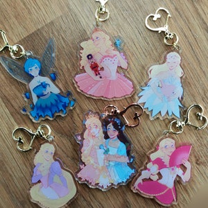 May include: Six clear acrylic keychains with different illustrations of women in various poses and outfits. The keychains feature gold-colored metal heart-shaped rings.