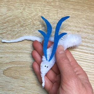 Könnte beinhalten: Ein weißer Pfeifenputzer-Wurm mit blauen Filzantennen. Der Wurm hat zwei schwarze Augen.