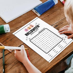 May include: A black and white Halloween word search puzzle with a grid of letters and a list of words to find. The puzzle features a graphic of three orange pumpkins with black eyes and mouths.