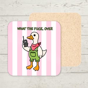 Op de afbeelding: Vierkante onderzetter met een cartoon eend in groene tuinbroek en een rode bandana, die een walkie-talkie vasthoudt. De onderzetter heeft een roze en witte gestreepte achtergrond en de tekst "WHAT THE FUCK, OVER". Een tweede kurken onderzetter is zichtbaar.