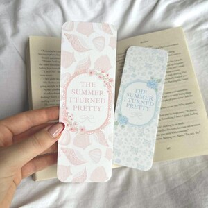 Op de afbeelding: Twee rechthoekige bladwijzers met de tekst "THE SUMMER I TURNED PRETTY". E&eacute;n bladwijzer heeft een roze schelpenpatroon en bloemaccenten. De andere heeft een blauw bloemenpatroon.