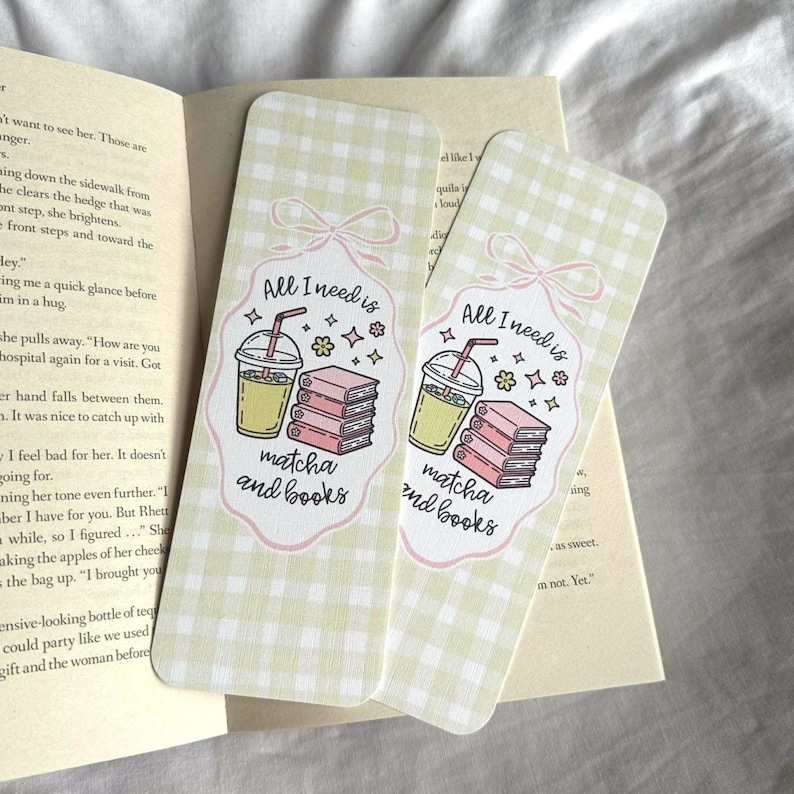 Op de afbeelding: Twee rechthoekige bladwijzers met een lichtgroen ruitpatroon. Elke bladwijzer heeft een cartoonillustratie van een matcha-drankje, boeken en de tekst "All I need is matcha and books."