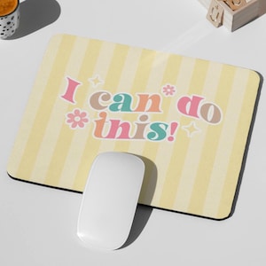 Peut inclure: Tapis de souris rectangulaire avec un fond à rayures jaunes et le texte "I can do this!" en lettres colorées. Une souris d'ordinateur blanche est positionnée sur le tapis.