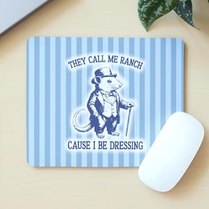 May include: A blue and white striped mouse mat featuring a cartoon rat in a suit, hat, and cane. The text reads "THEY CALL ME RANCH CAUSE I BE DRESSING". A white computer mouse is positioned beside the mat.