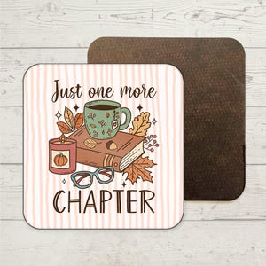 May include: Square coaster with a fall theme. The coaster features a candle, a teacup, a book, and eyeglasses. The text on the coaster reads "Just one more CHAPTER". The background has vertical stripes in a light peach colour.